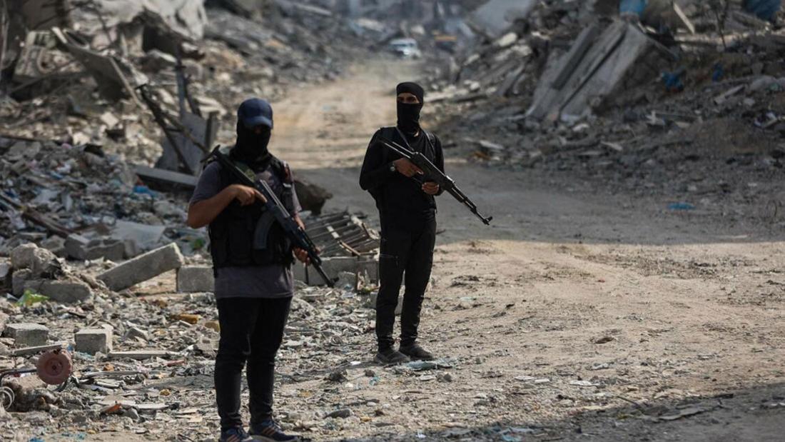 Zwei bewaffnete Männer stehen zwischen Schutt und Asche