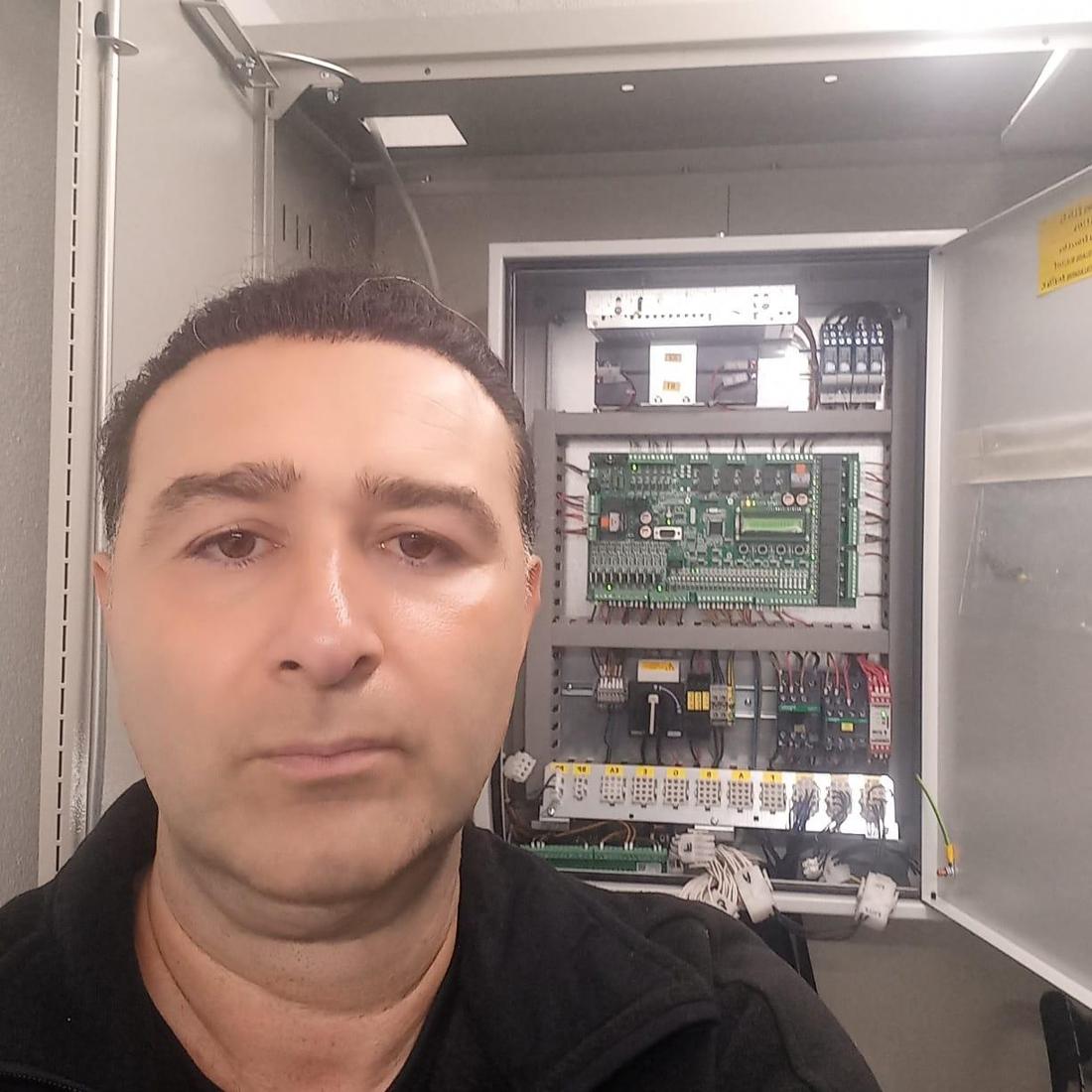 Hasan Amani kennt sich mit Aufzügen aus und steht vor einem Schaltkasten.