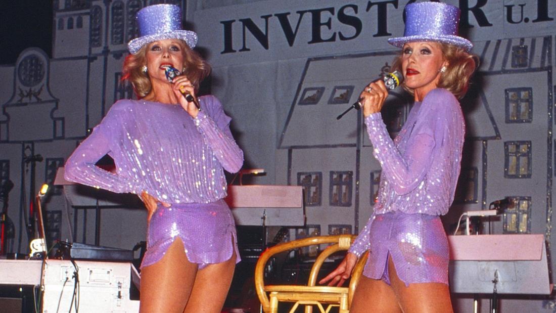 Die Kessler-Zwillinge in funkelnden lila Outfits bei einem ihrer spektakulären Bühnenauftritte.