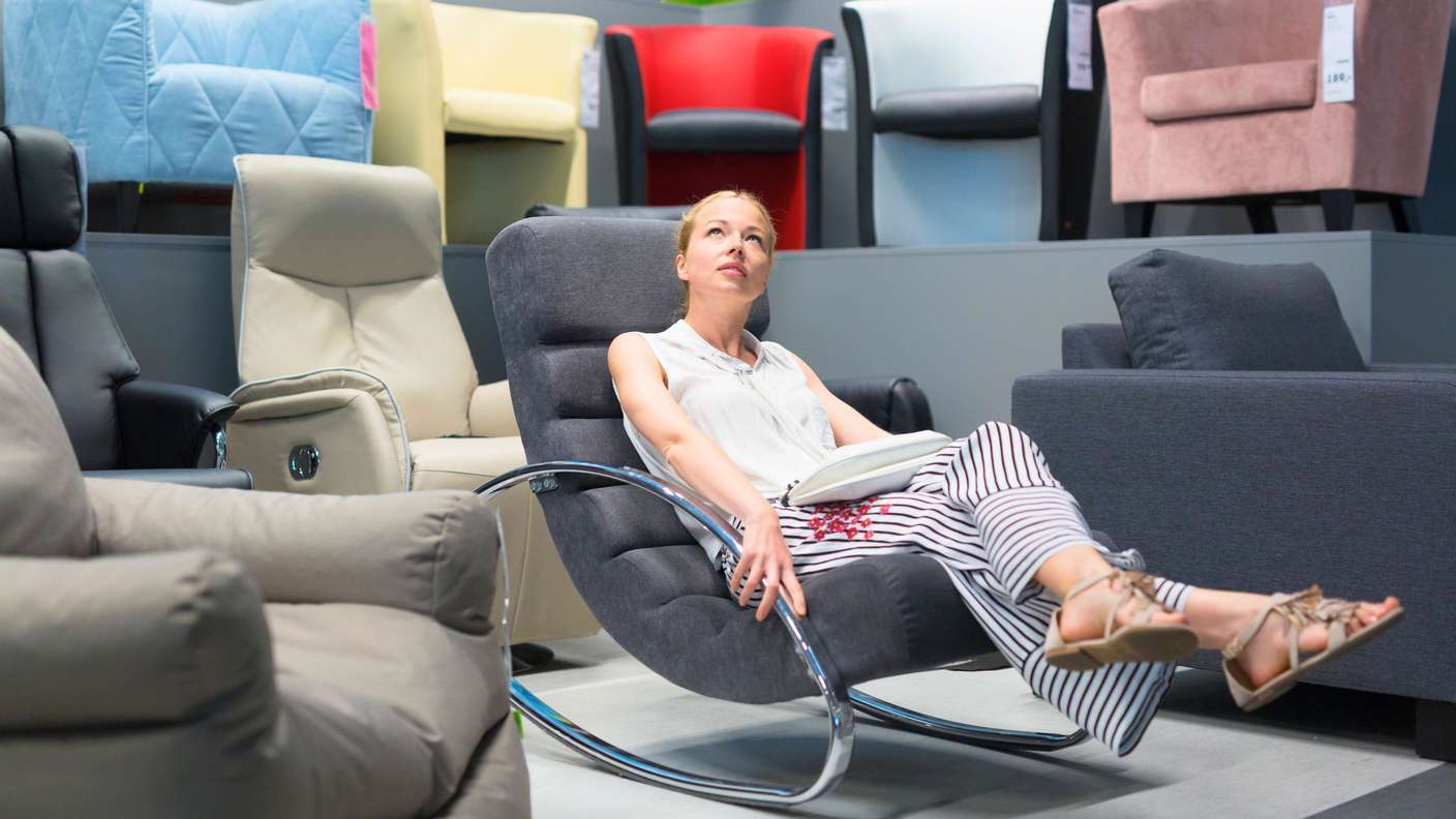 Eine Frau schaut sich Sessel im Möbelhaus an