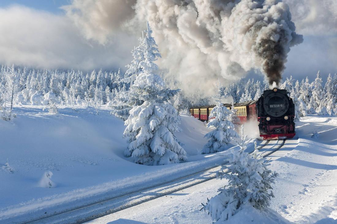 Tief verschneite Winterlandschaft mit schneebedecktem Fichtenwald, die Brockenbahn fährt zum Gipfel des Brocken, Nationa
