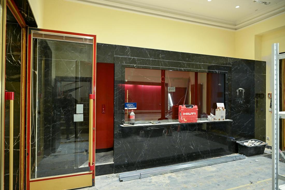 Zu sehen ist der Eingangsbereich der Caligari Filmbühne in Wiesbaden. Auf dem Boden steht eine Bauwanne mit Schutt, daneben liegen Kabelkanäle. Die Wände , gestrichen in leuchtendem Gelb, sollen werden diese Farbe behalten. 