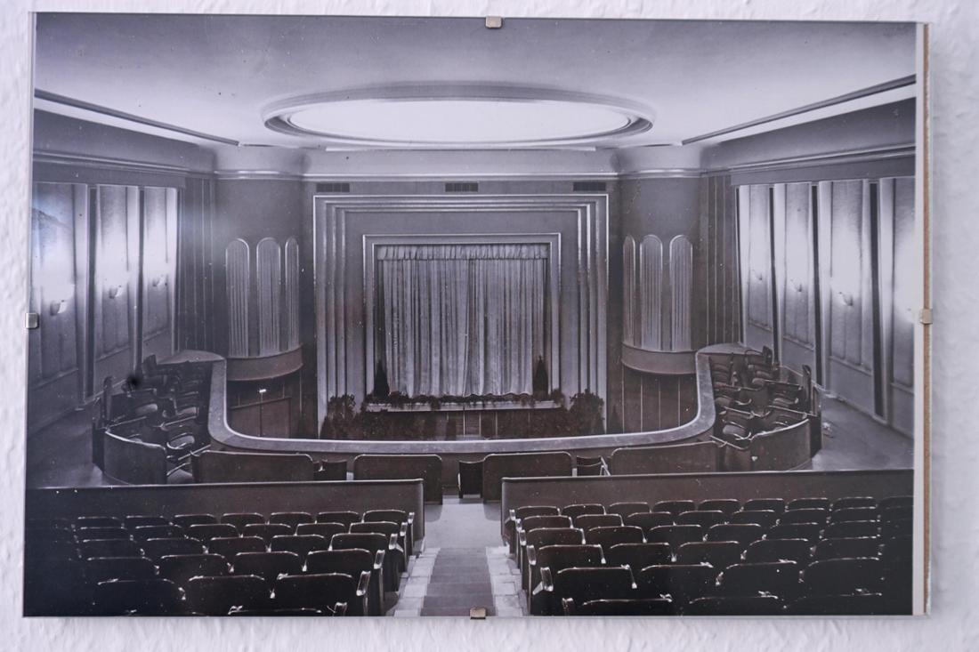 Das Repro eines historischen Fotos der Caligari Filmbühne in Wiesbaden zeigt das Kino, eröffnet 1926, in seiner ursprünglichen Ausstattung. Damals war die Dekoration schlichter. Ein Vorhang verdeckt die große Leinwand des Stummfilmkinos. 