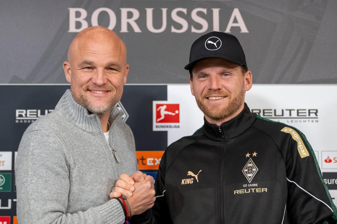 Eugen Polanski und Rouven Schröder haben vor der Pressekonferenz von Borussia Mönchengladbach für ein gemeinsames Foto posiert. Der Trainer und der Sportchef geben sich die Hand.