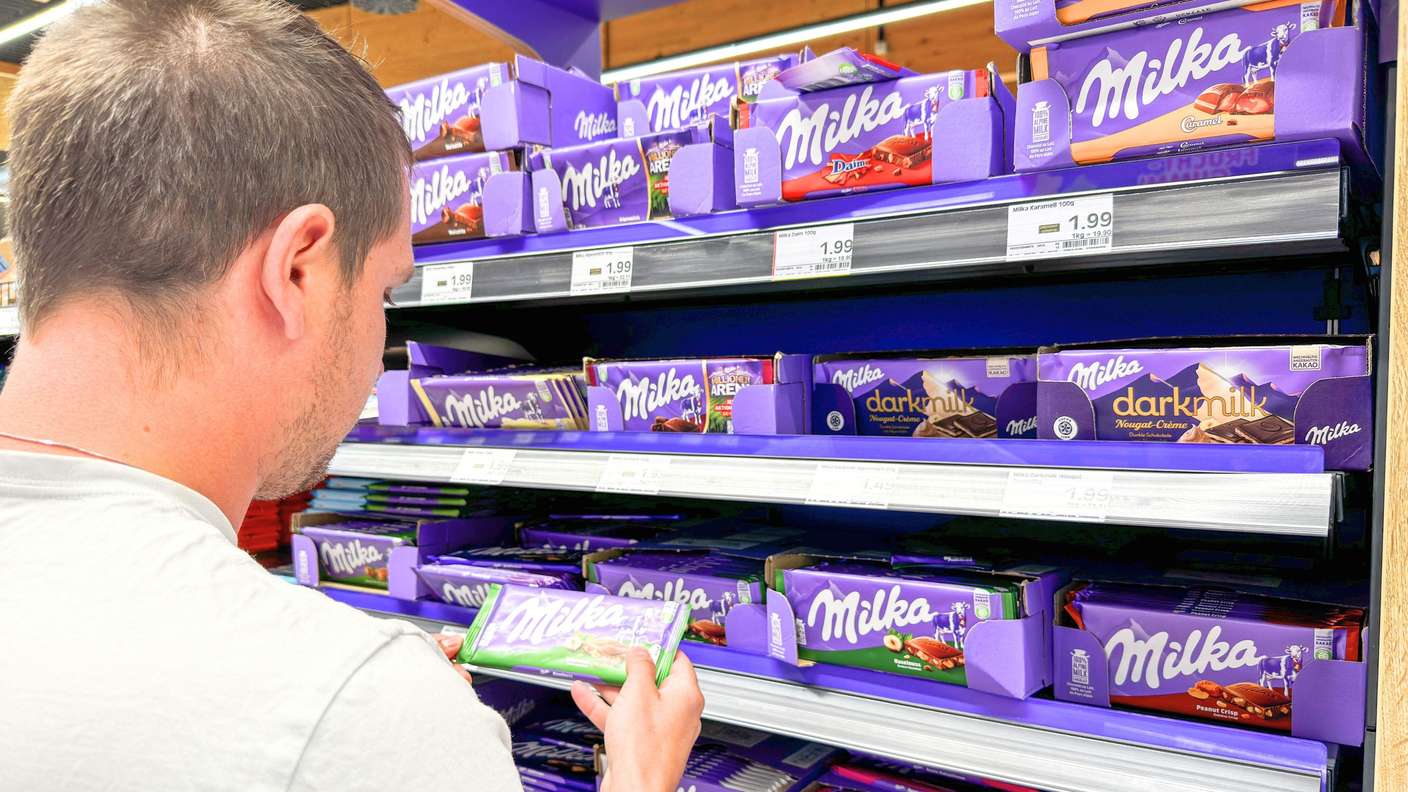 Ein Mann schaut sich Milka-Tafel im Supermarkt an