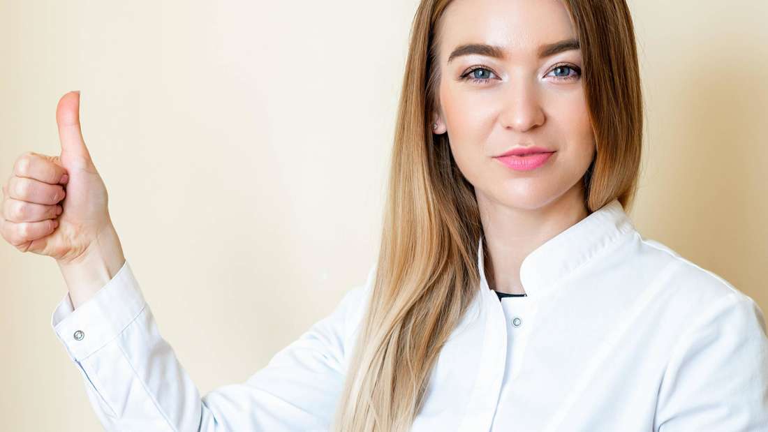 Die junge Frau zeigt die Daumen nach oben