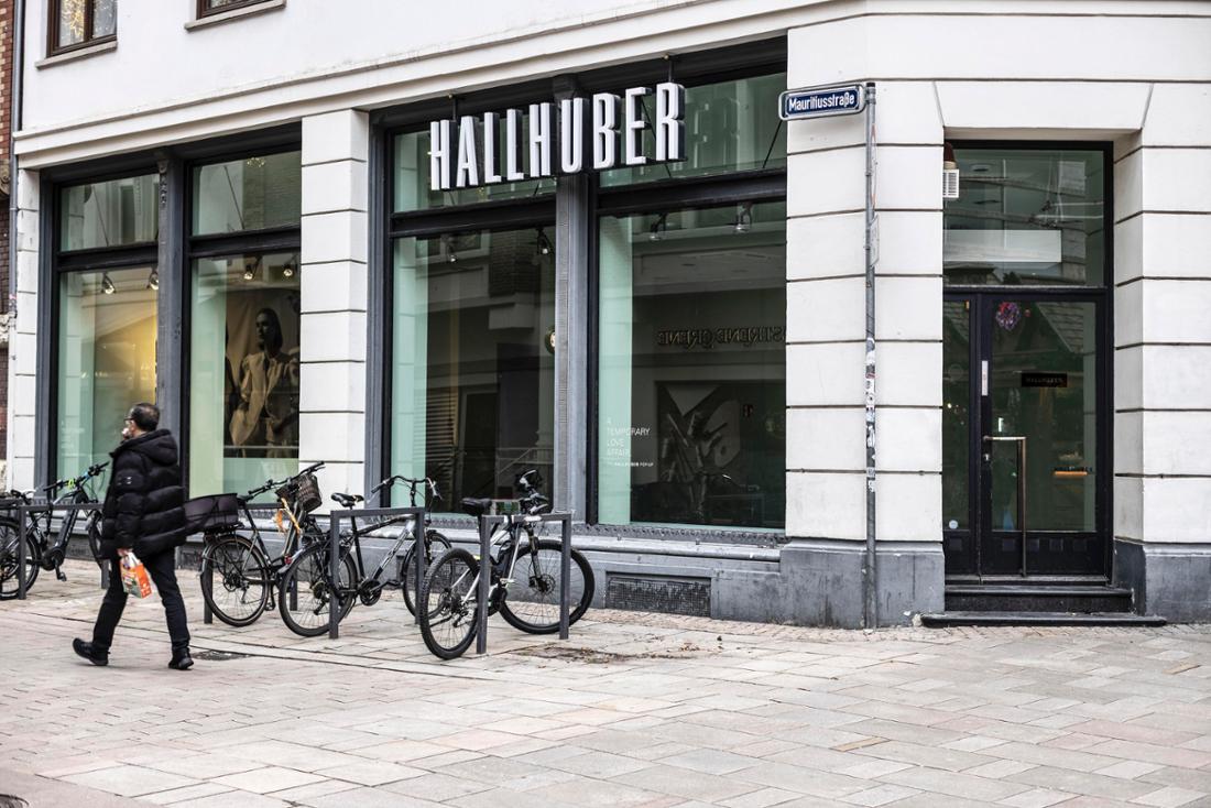 Ein Mann läuft an einem leeren Schaufenster vorbei. Schilder weisen darauf hin, dass sich dort früher eine Hallhuber-Filiale befunden hat. Vor dem Geschäft sind Fahrräder abgestellt. 