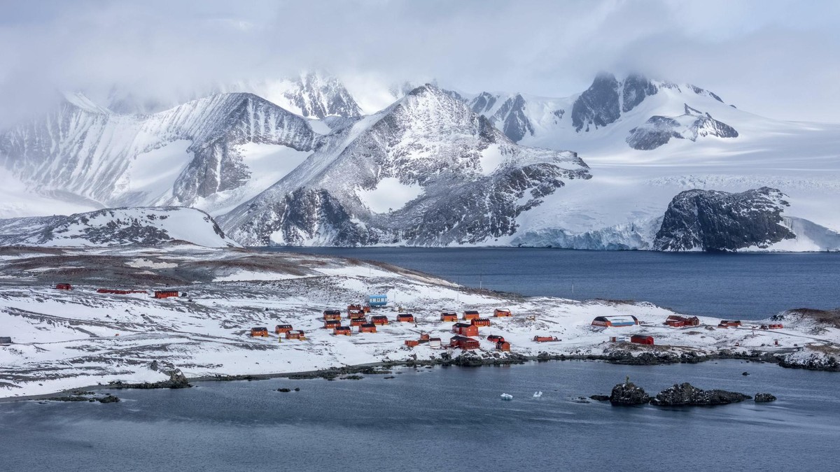 Aerial view of the research station nestled on the snow-covered land, contrasting with the dark blue waters and the distant snow-capped mountains, Seymour Island, Antarctica.