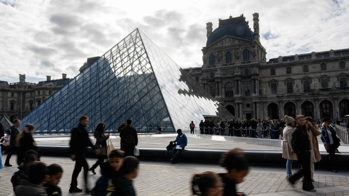 Menschen spazieren vor dem Louvre entlang