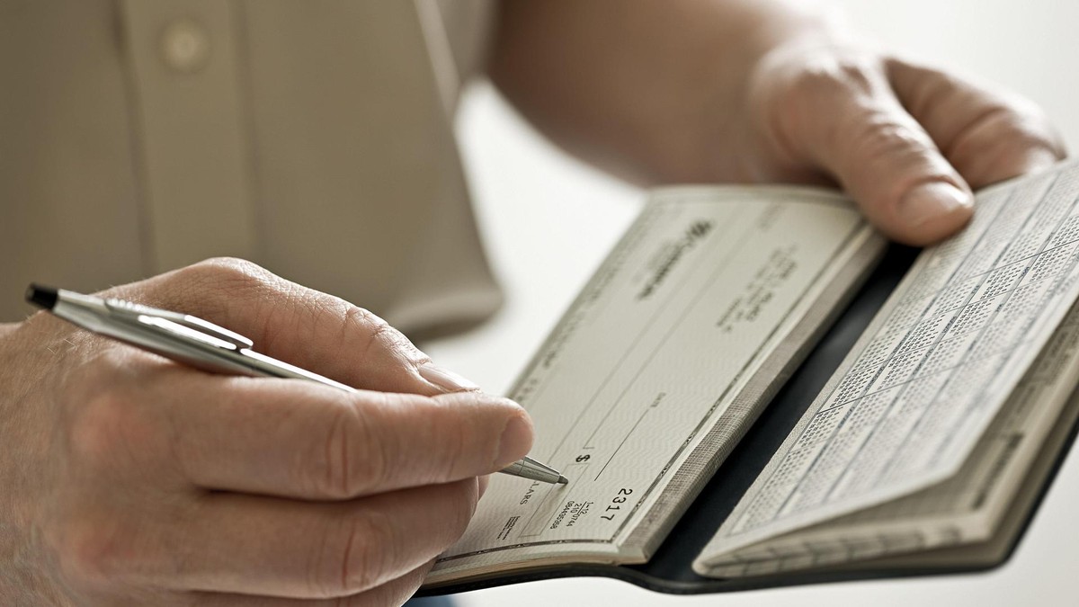 Das Scheckbuch: 2007 zählte die Bundesbank 75,5 Millionen Schecks. A man holding a cheque book