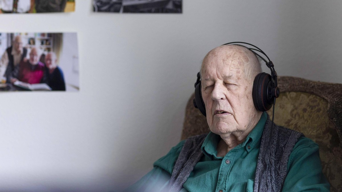 Alter Mann im Pflegeheim hoert Musik mit Kopfhoerer. Old man in nursing home listening to music with headphones. Heidelb