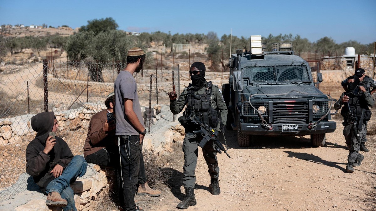 Viel zu selten greift die israelische Grenzpolizei ein und hindert radikale Siedler daran, Palästinenser bei der Olivenernte anzugreifen. An Israeli border police officer holds back an Israeli settler trying to prevent Palestinians from harvesting olives, in Silwad