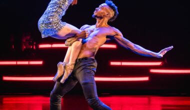 Zu sehen ist eine Tänzerin im Glitzerkleid und ein Tänzer mit freiem Oberkörper auf der Bühne.