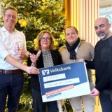 Murat Durmaz, Niklas Hammann, Dagmar Hammann und Jan Hindrichs stehen vor einem Weihnachtsbaum und halten einen überdimensionierten Scheck in Händen.