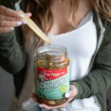 Eine Frau nimmt eine Gewürzgurke aus dem Glas.