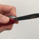 Männliche Hand hält ein ausgeklapptes Taschenmesser.
