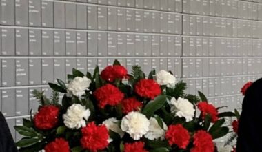 Blumen zwischen Schultern vor der Wand der Namen.