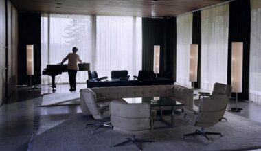 Eine Doppelgängerin von Angela Merkel steht an einem Flügel im Kanzlerbungalow.