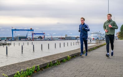 Laufguide Mathis Brandt (23, rechts) von Running City Tours ist unterwegs mit KN-Reporter Moritz Krüger joggend die Stadt zu entdecken. Ausch ein Blick auf die Kreuzfahrer und die Portalkräne von German Naval Yards gehört dazu.