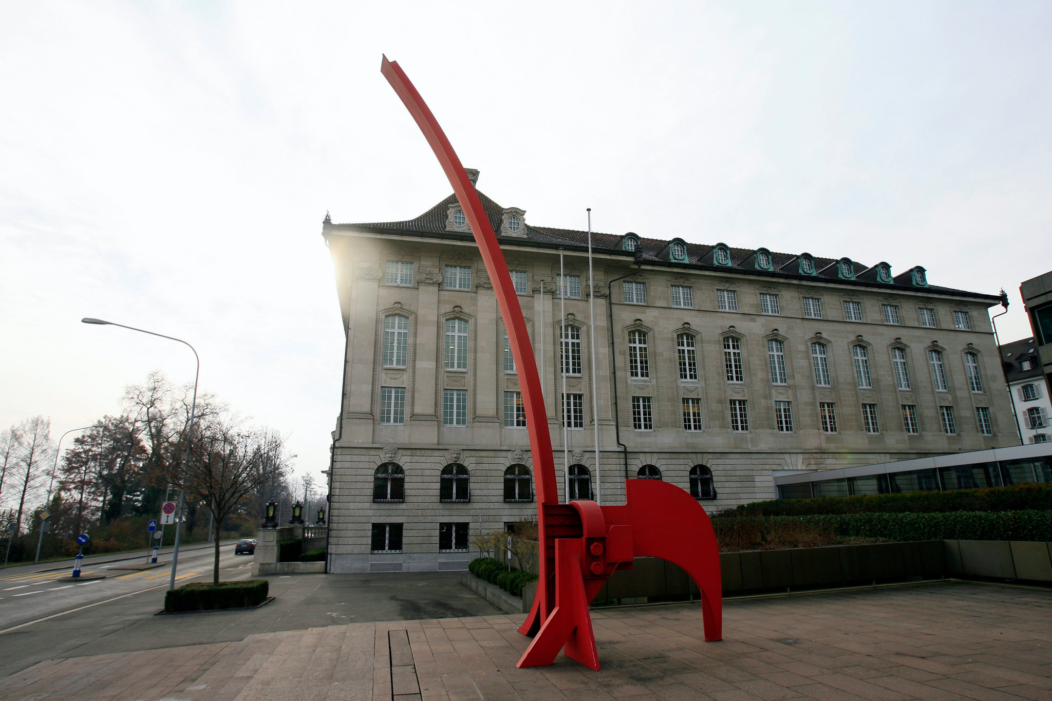 Hauptsitz von Swiss Re am Mythenquai in Zürich mit der roten Eisenskulptur "Grosse Giraffe" im Vordergrund, fotografiert an einem bewölkten Tag.