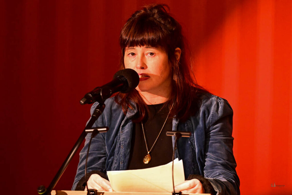 Eva-Maria Damasko trägt den Beitra von Ellen Brenner vor: „Gruß an die Menschneit"