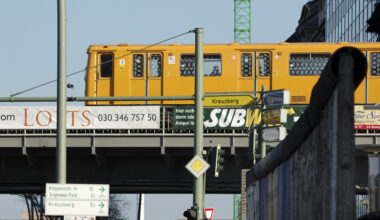 Eine gelbe Berliner Stadtbahn auf einer Brücke.