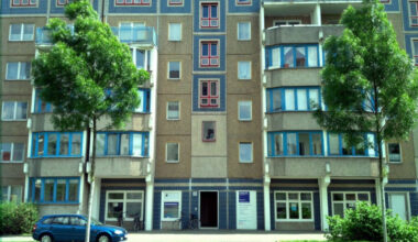 Hausfassade mit Bäumen und Wiese.