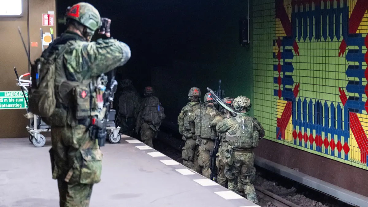 Nachdem der Bahnsteig im Rahmen der Übung "Bollwerk Bärlin" gesichert wurde, betreten Bundeswehrsoldaten ein Gleisbett. Dieses ist Teil eines Übungstunnels der BVG.