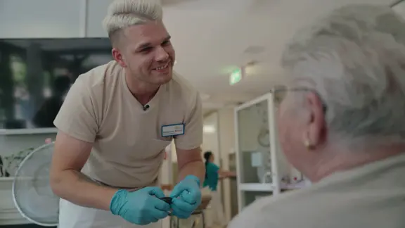 Ein Krankenfpfleger lächelt eine Patientin an.