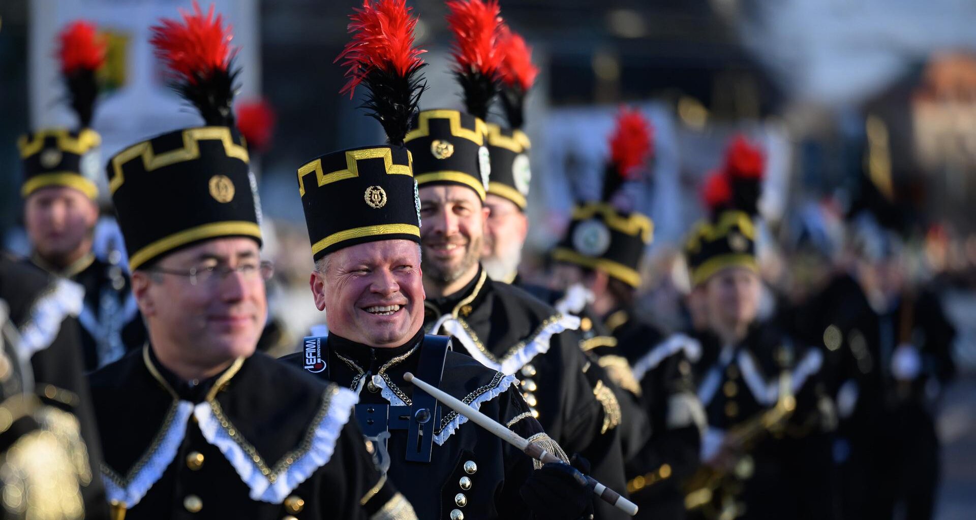 Teilnehmer der Bergparade gehen nebeneinander. Sie sind in traditioneller Bergmanns-Uniform gekleidet.