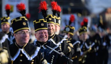 Teilnehmer der Bergparade gehen nebeneinander. Sie sind in traditioneller Bergmanns-Uniform gekleidet.