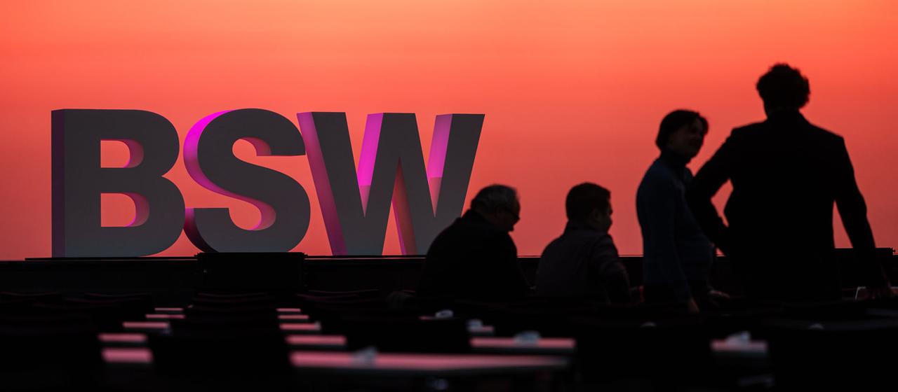 Menschen stehen vor einem BSW Schriftzug in Bonn. | dpa Menschen stehen vor einem BSW Schriftzug in Bonn.