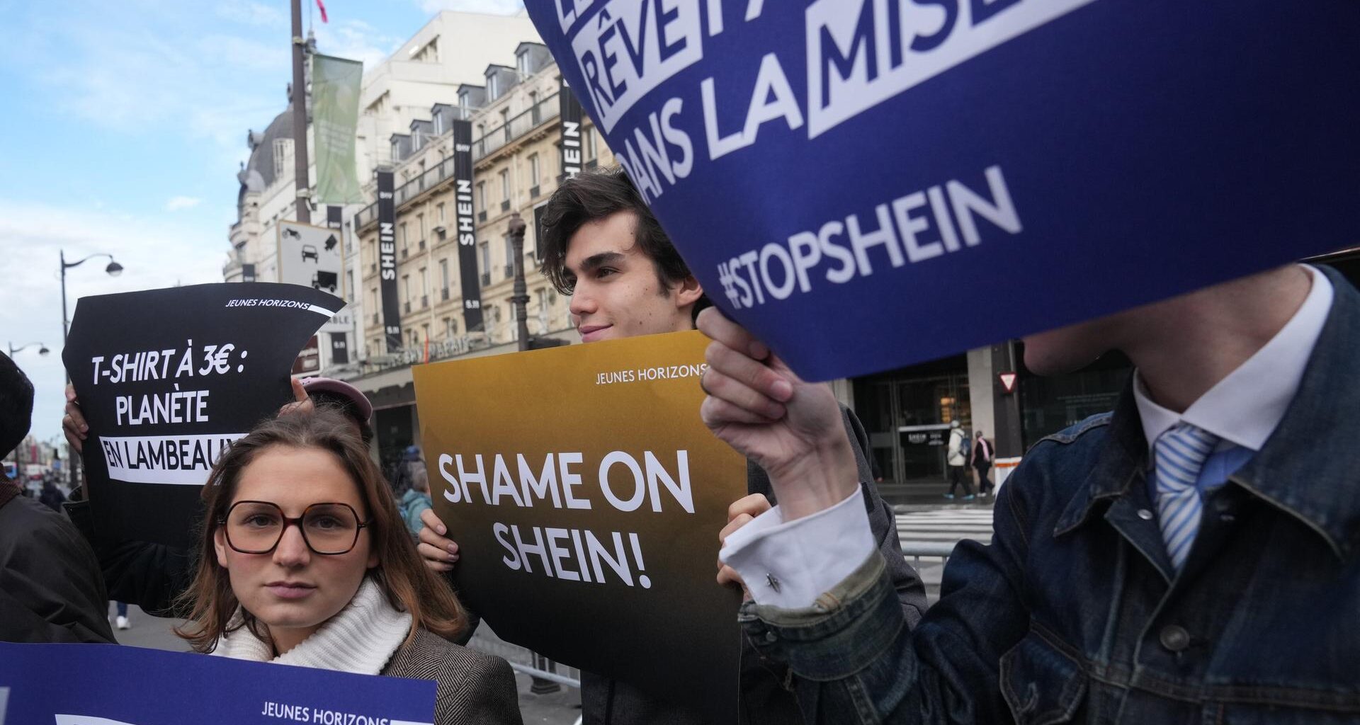 Demonstranten halten Plakate vor dem Kaufhaus BHV in Paris, wo der Fast-Fashion-Gigant Shein am 5. November 2025 seine erste permanente Filiale eröffnet hat.