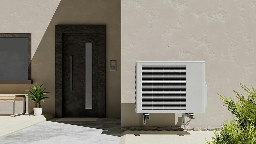 Wärmepumpen-Außengerät als weißer Kasten nebeneinem Hauseingang