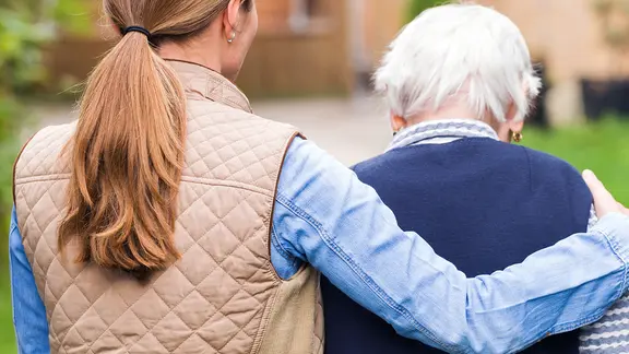 Eine junge Frau umarmt eine Ältere.