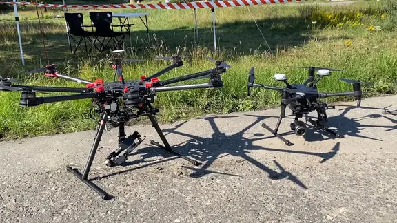 Zwei Drohnen stehen auf Asphalt.