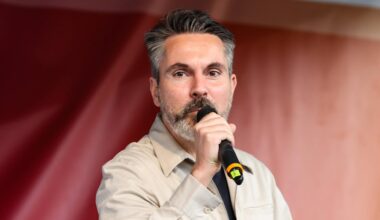 Fabio De Masi spricht in ein Handmikrofon. Im Hintergrund: ein rotes Transparent