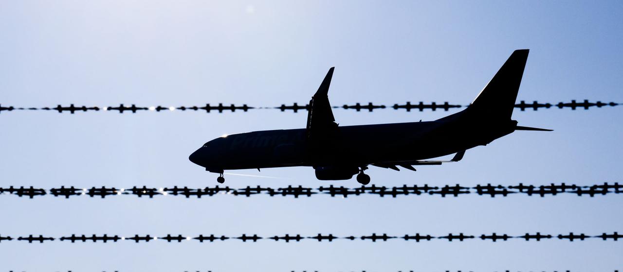 Ein Flugzeug fliegt hinter Stacheldraht am Flughafen Hannover.