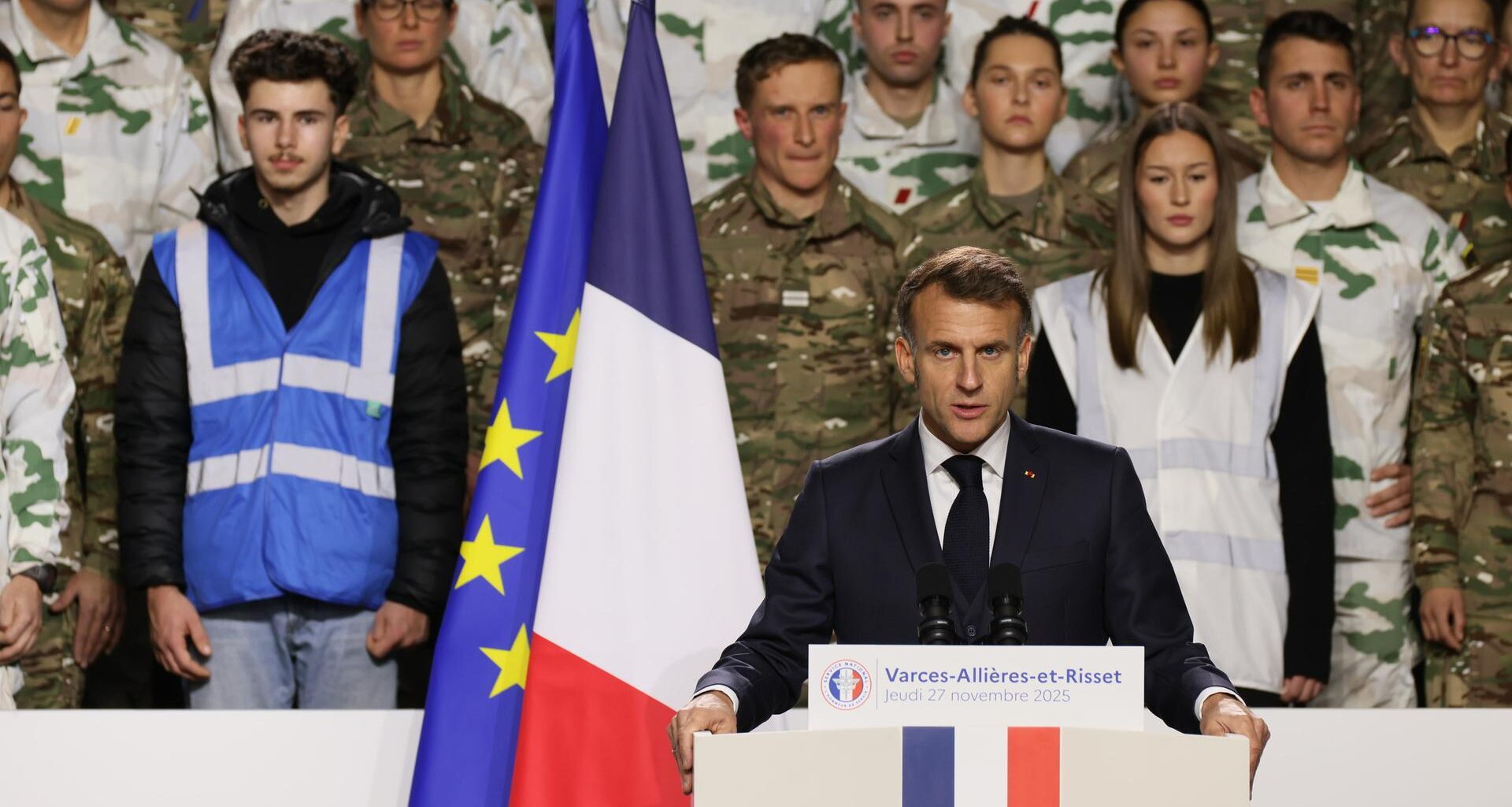 Präsident Macron steht hinter einem Rednerpult, hinter ihm die Landesfahne und Soldaten.