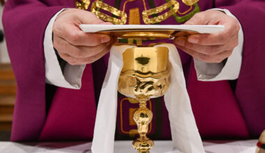 Ein Priester legt beim Gottesdienst die Palla auf den Kelch.