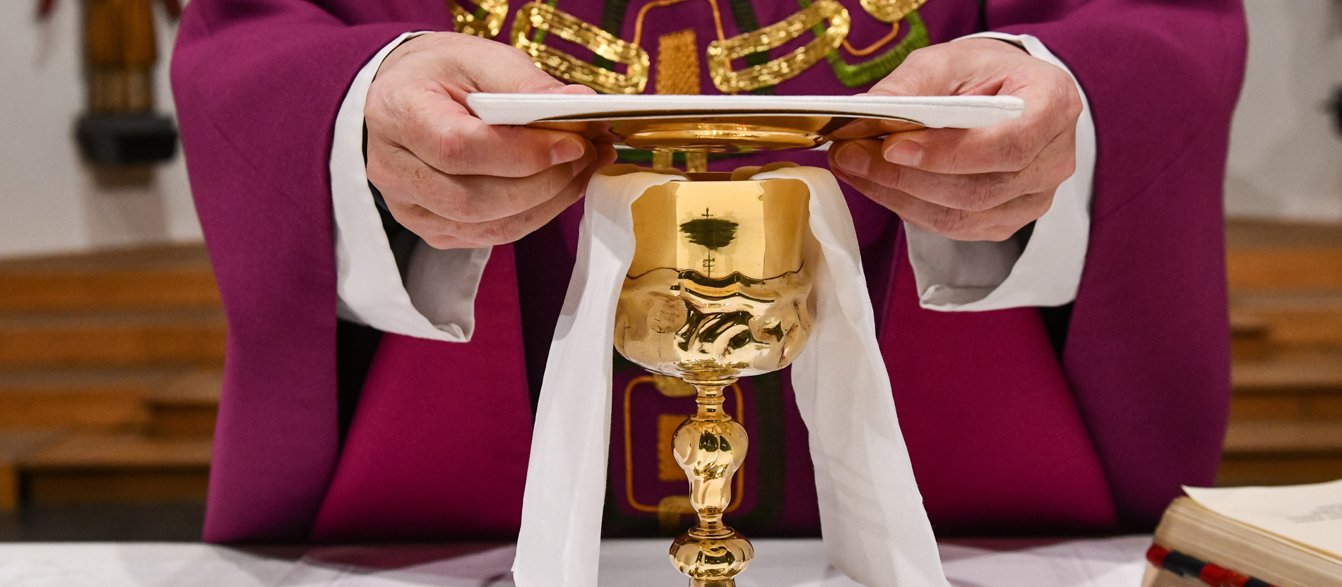 Ein Priester legt beim Gottesdienst die Palla auf den Kelch.
