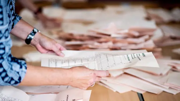 Eine Wahlhelferin sortiert in einer Grundschule, in der ein Wahllokal für die Kommunalwahl untergebracht ist, die Stimmzettel für die Auszählung.