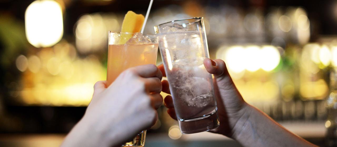 Zwei Menschen stoßen mit Longdrinks an. | picture alliance/dpa/dpa-Zentral Zwei Menschen stoßen mit Longdrinks an.