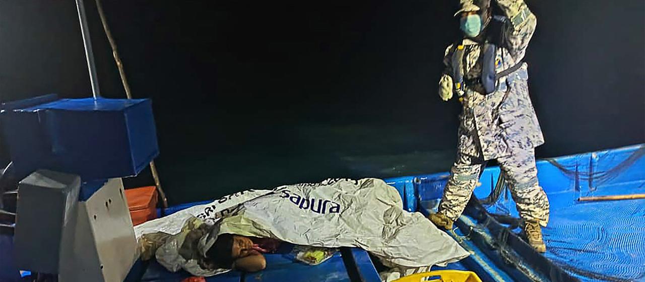 Ein Mitglied der malayischen Küstenwache mit Überlebenden eines Bootsunglücks. | AFP Ein Mitglied der malayischen Küstenwache mit Überlebenden eines Bootsunglücks.