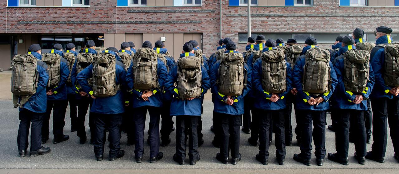 Zahlreiche Rekruten der Marine stehen mit Rucksäcken vor einer Unterkunft im Marinestützpunkt Wilhelmshaven, Niedersachsen.