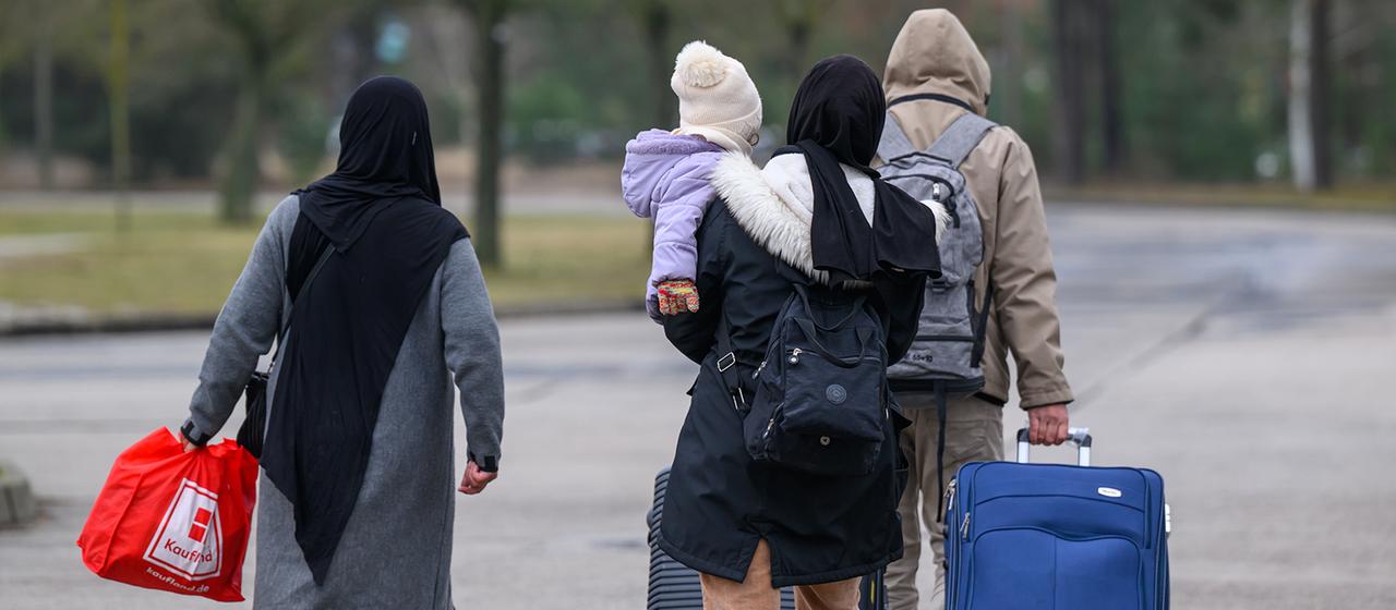 Migranten verlassen mit Reisegepäck das Gelände der Zentralen Ausländerbehörde Brandenburgs (ZABH).