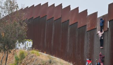 Eine kleine Gruppe von Migranten, darunter mindestens ein Kind, versucht, mit einer Leiter über die Grenzmauer in die USA zu gelangen.