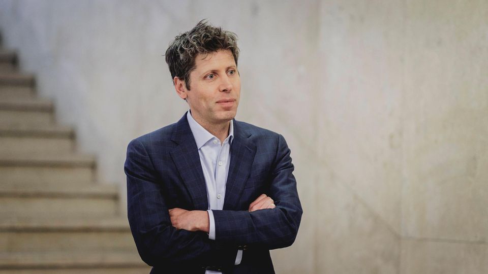 Sam Altman trägt Hemd und Sakko und steht mit verschränkten Armen in einem Treppenhaus Sam Altman trägt Hemd und Sakko und steht mit verschränkten Armen in einem Treppenhaus
