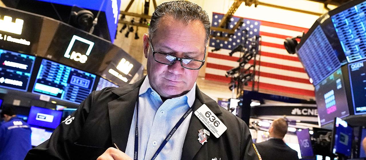 Börsenhändler auf dem Parkett der New Yorker Börse schaut auf ein Tablet.