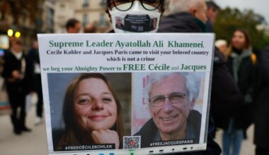 Eine Frau hält ein Plakat mit einem Bild von Cécile Kohler und Jacques Paris, die im Mai 2022 während einer Touristenreise in den Iran verhaftet wurden.